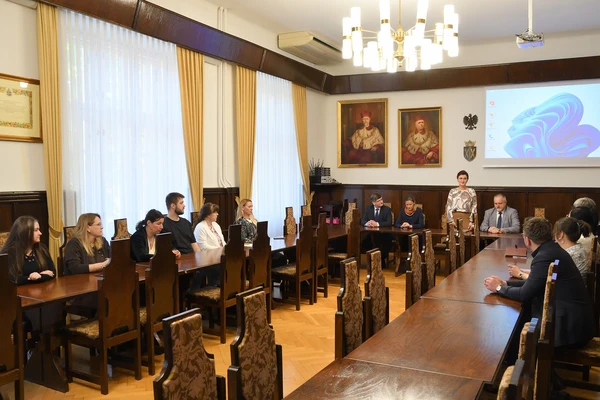 14 osób uczestniczących w spotkaniu podsumowującym Krakowskie Dni Integracji siedzących za stolikami