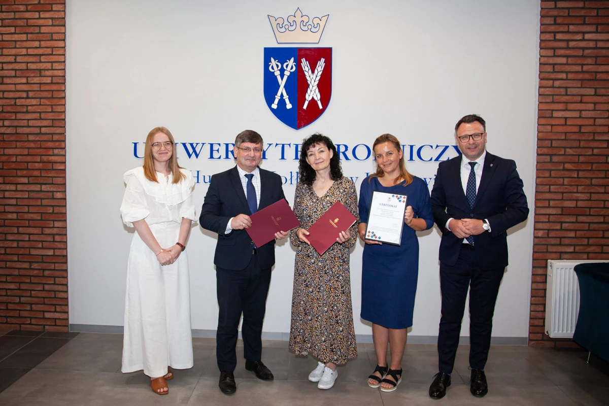 Uczestnicy spotkania pozują do zdjęcia, stojąc na tle logotypu Uniwersytetu Rolniczego.